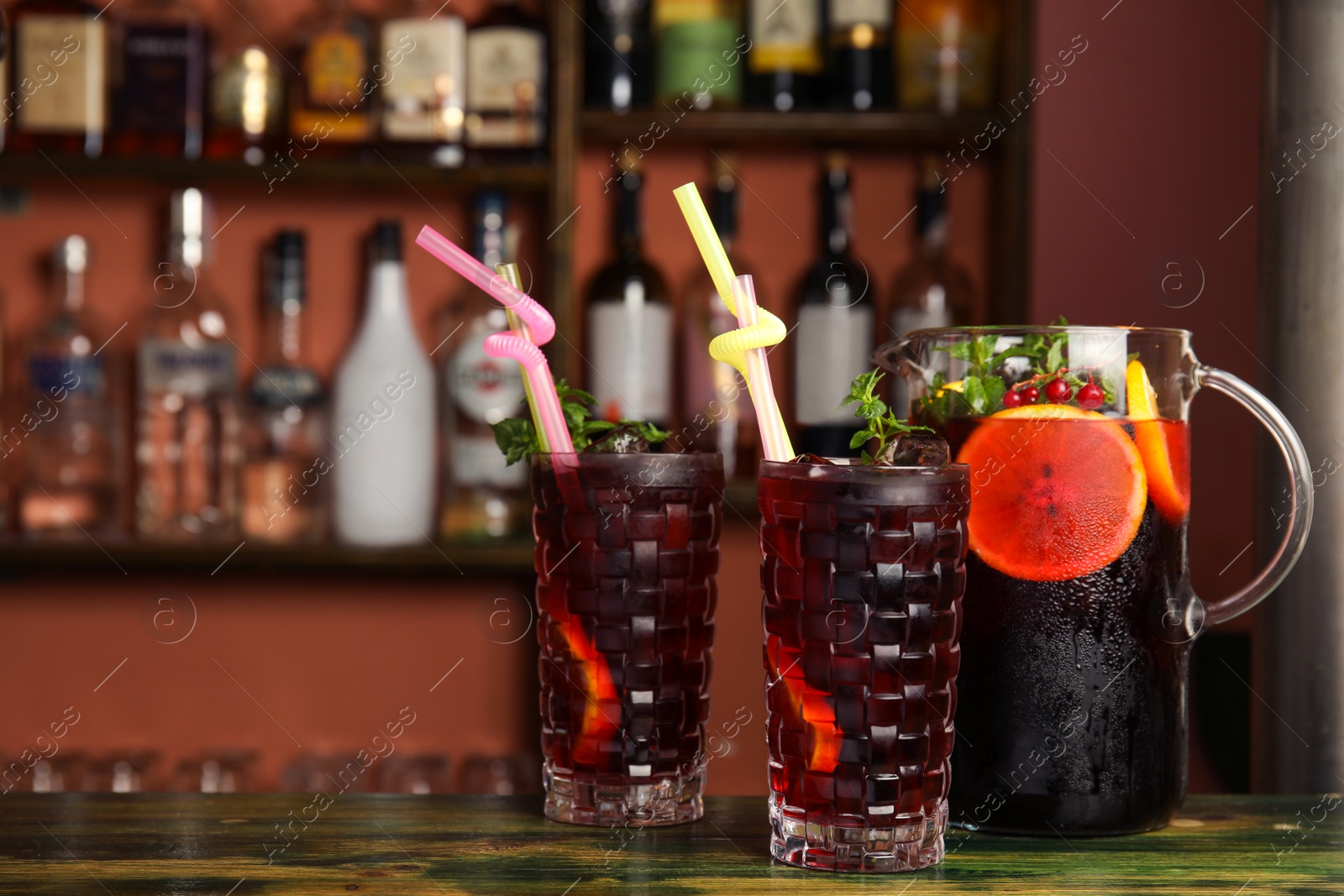 Photo of Glasses and jug with delicious cocktail on counter in cafe