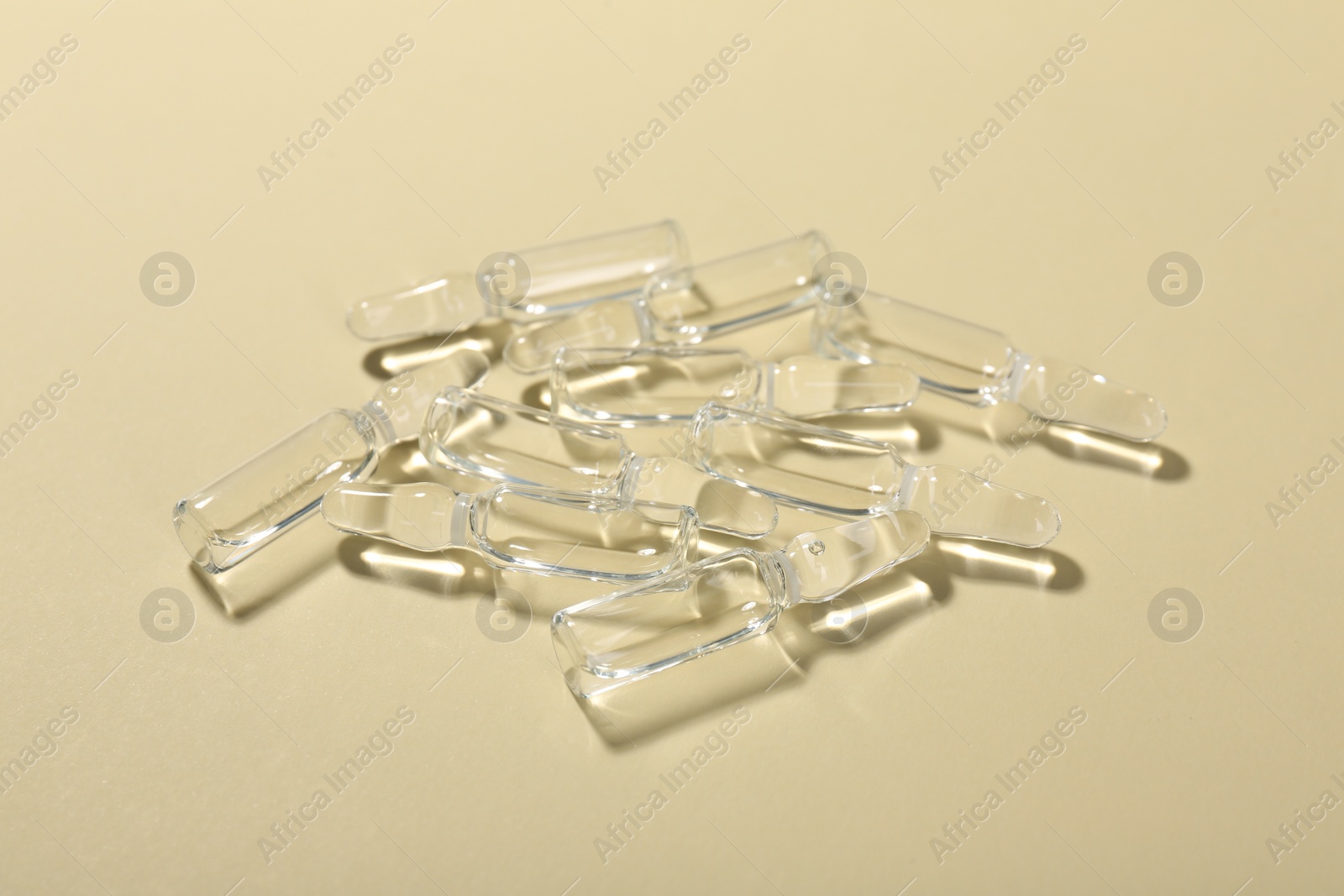 Photo of Glass ampoules with liquid on beige background