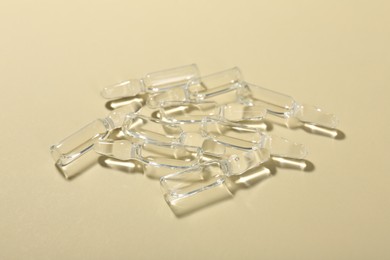 Photo of Glass ampoules with liquid on beige background