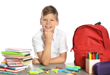 Photo of Schoolboy at table with stationery against white background