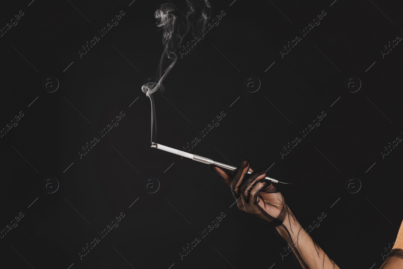 Photo of Woman holding long cigarette holder on black background, closeup