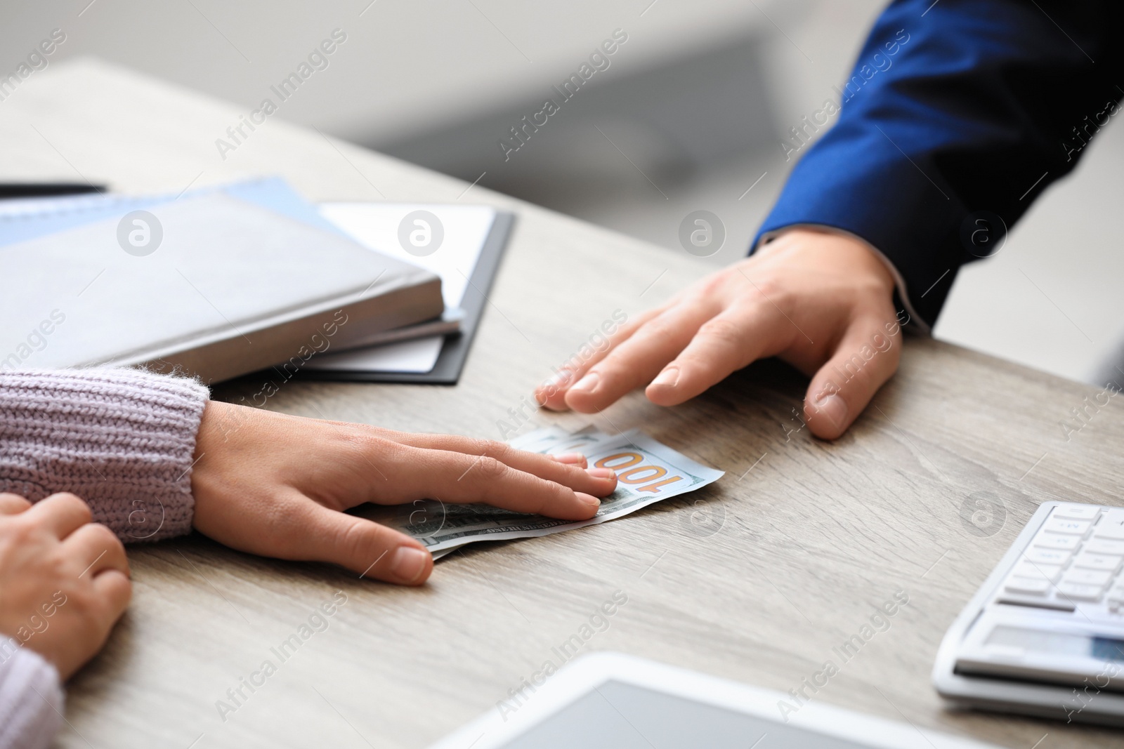 Photo of Woman offering bribe money at table indoors, closeup