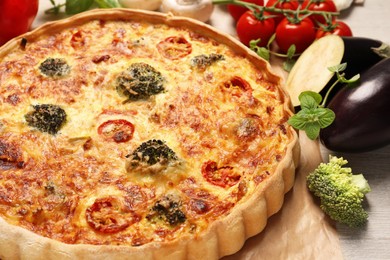 Photo of Delicious homemade vegetable quiche, broccoli, zucchini and oregano on table, closeup