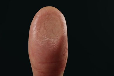 Photo of Man pressing control glass of biometric fingerprint scanner on dark background, closeup. Space for text