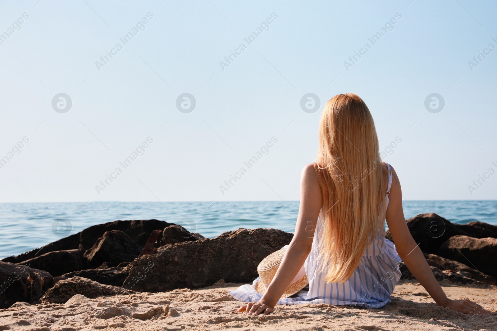 Photo of Young woman near sea on sunny day in summer, back view