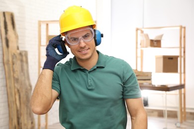 Worker wearing safety headphones indoors. Hearing protection device