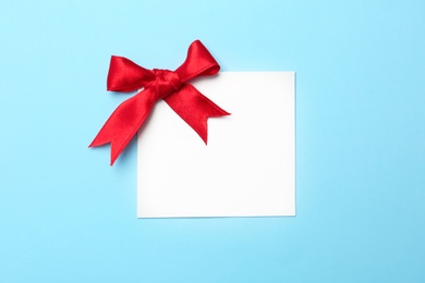 Photo of Blank gift tag with satin ribbon on color background, top view