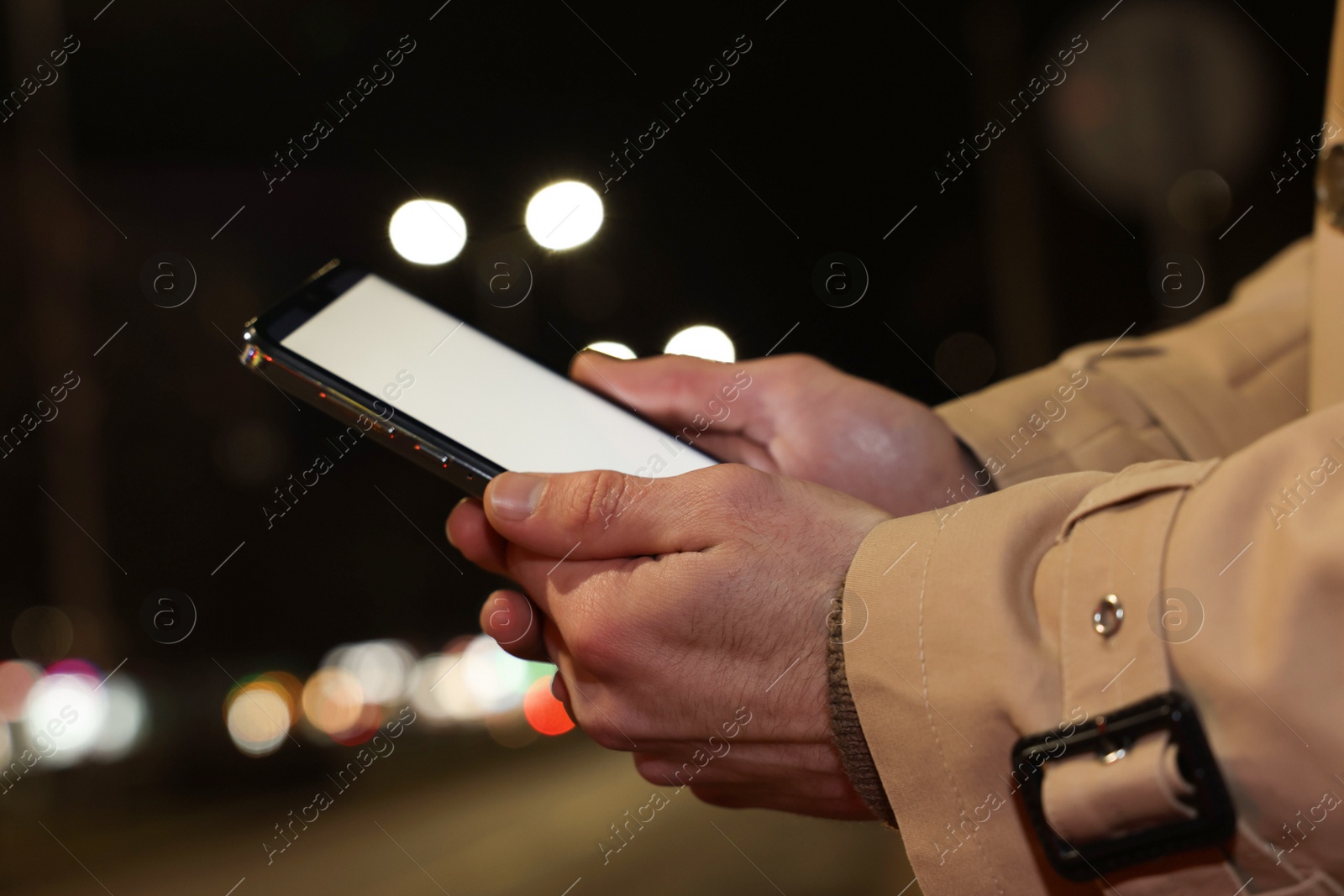 Photo of Man using smartphone on night city street, closeup