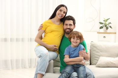 Family portrait of pregnant mother, father and son in house