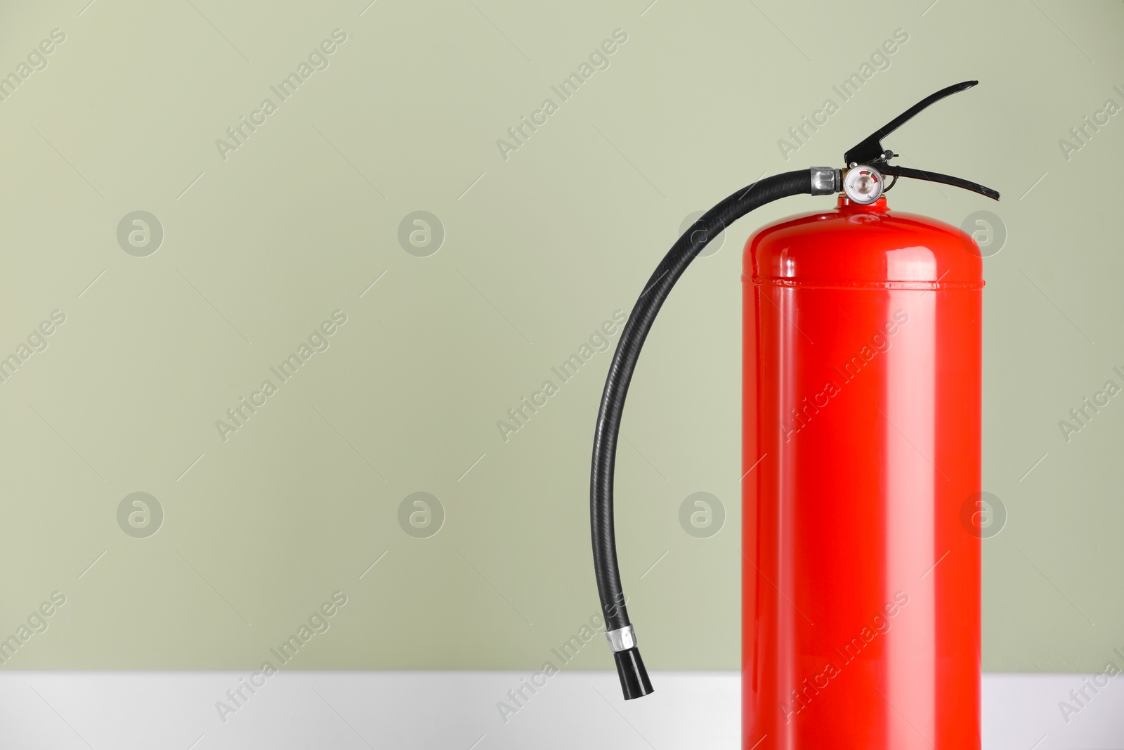 Photo of Fire extinguisher near pale green wall, space for text
