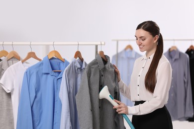 Woman steaming shirt on hanger in room