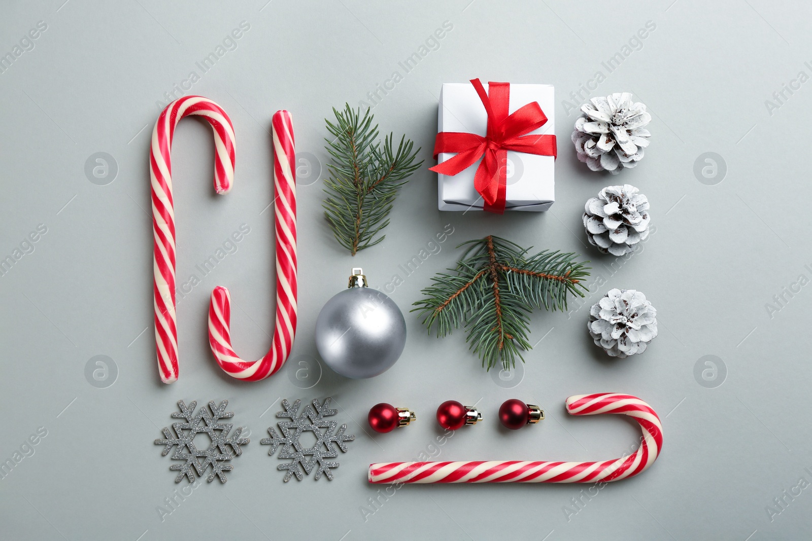 Photo of Flat lay composition with candy canes and Christmas decor on grey background