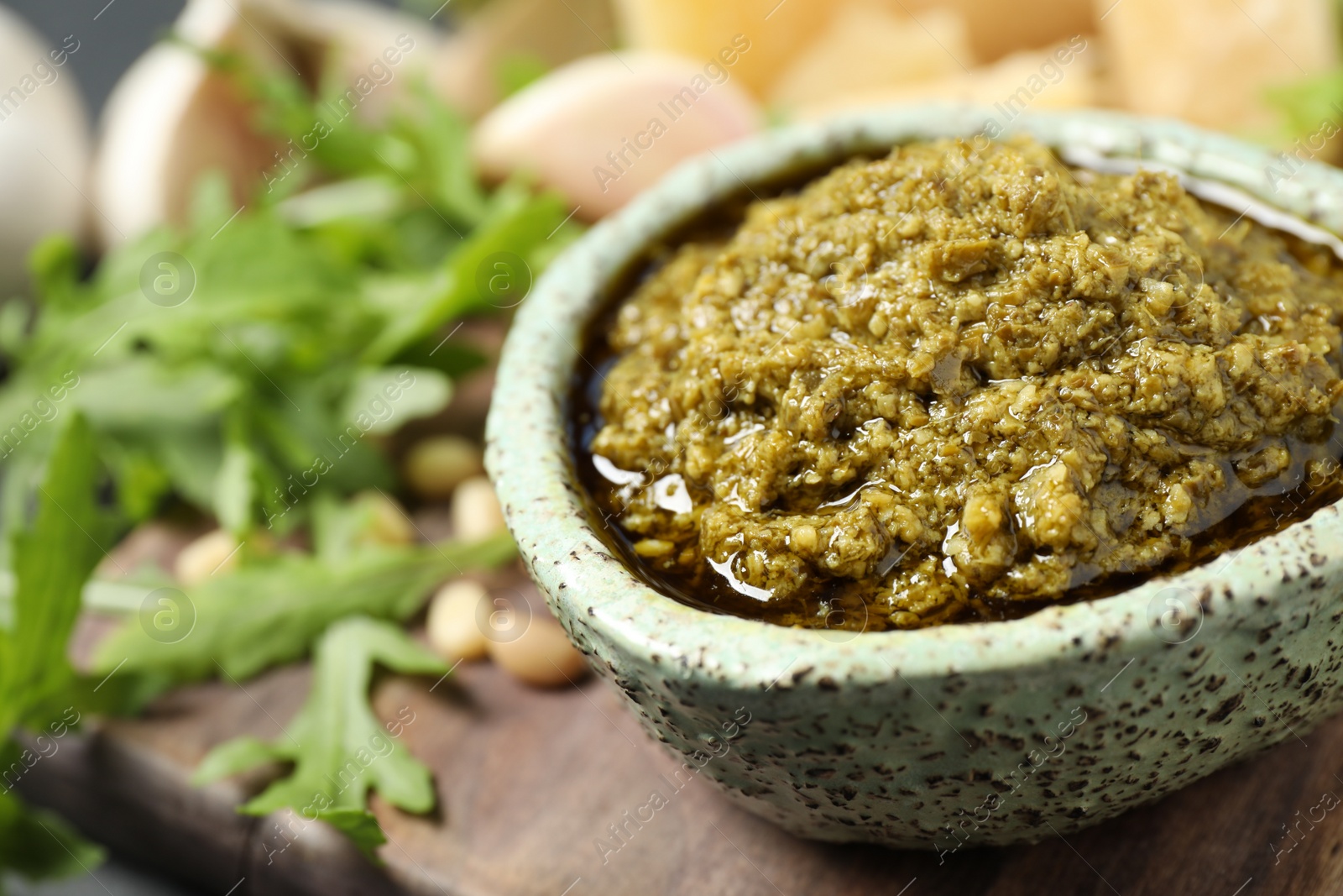 Photo of Bowl of tasty arugula pesto on table, closeup