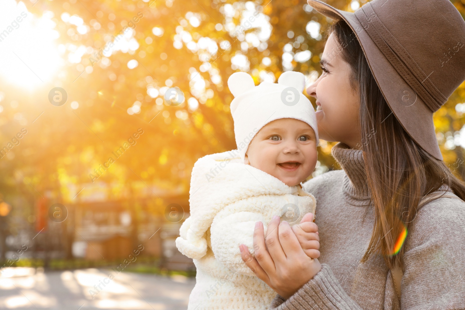 Photo of Happy mother with her baby daughter outdoors on autumn day, space for text