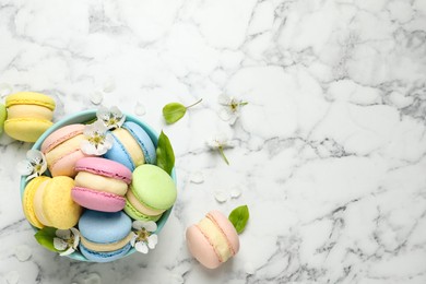 Photo of Delicious colorful macarons and flowers on white marble table, flat lay. Space for text