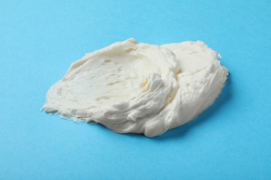 Photo of Smear of delicious cream cheese on light blue background