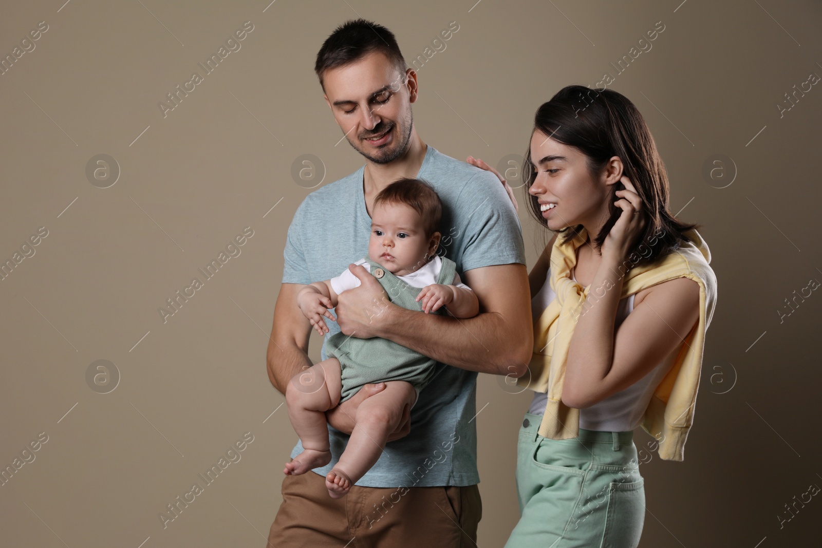 Photo of Happy family. Couple with their cute baby on beige background, space for text