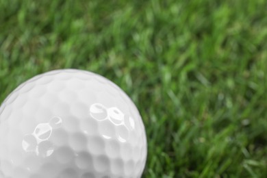 Photo of Golf ball on green grass, closeup. Space for text