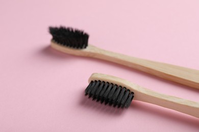 Two bamboo toothbrushes on pink background, closeup