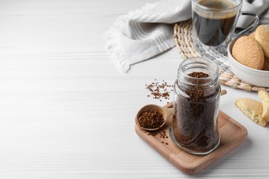 Photo of Jar of instant coffee and spoon on white wooden table. Space for text
