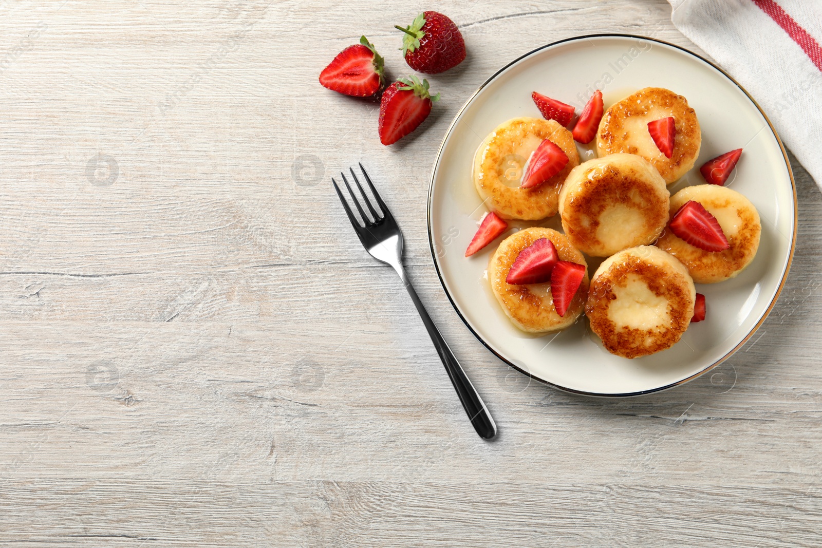 Photo of Delicious cottage cheese pancakes with strawberries and honey on white wooden table, flat lay. Space for text