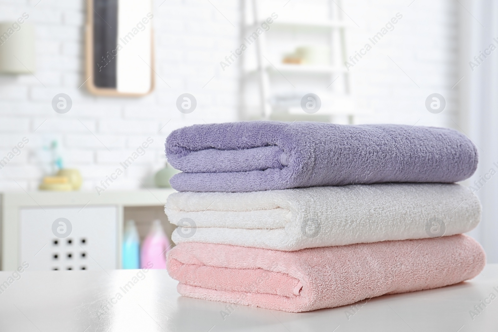 Photo of Stack of fresh towels on table in bathroom. Space for text