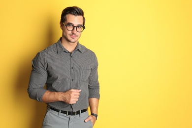 Photo of Young male teacher with glasses on yellow background. Space for text