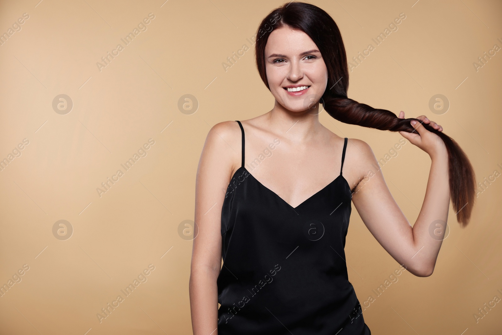 Photo of Portrait of beautiful young woman with healthy strong hair on beige background. Space for text