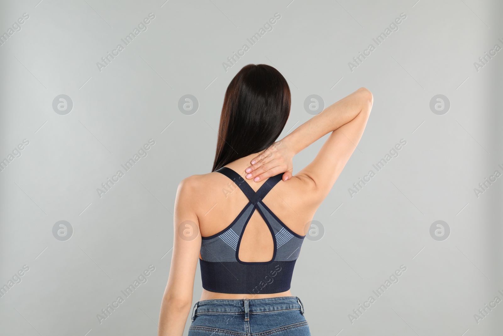 Photo of Woman suffering from pain in neck on light grey background. Visiting orthopedist