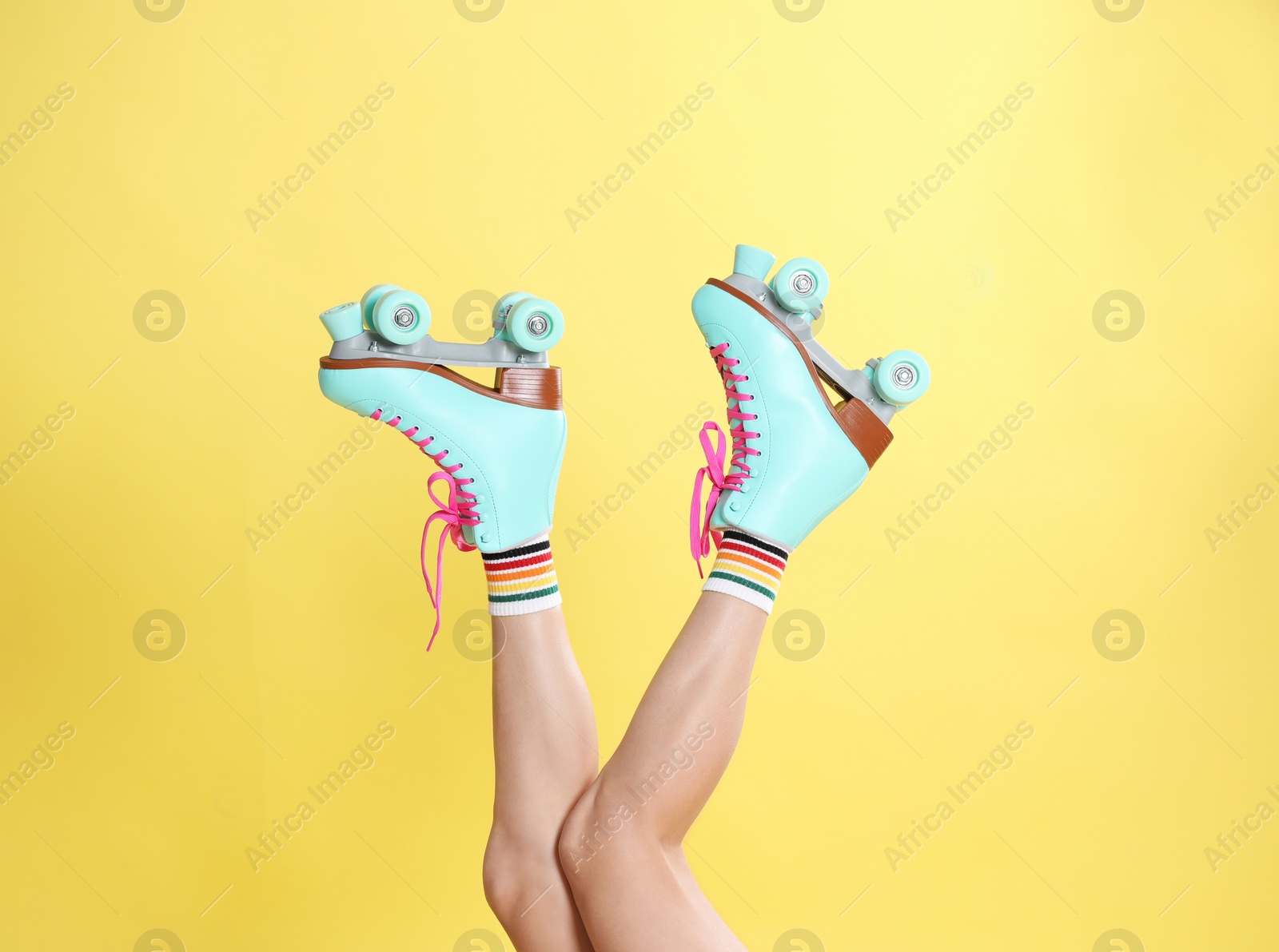 Photo of Young woman with retro roller skates on color background, closeup