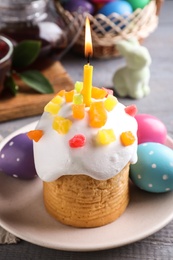 Photo of Traditional Easter cake with burning candle on grey wooden table