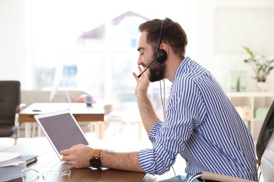 Young man using video chat on laptop in home office