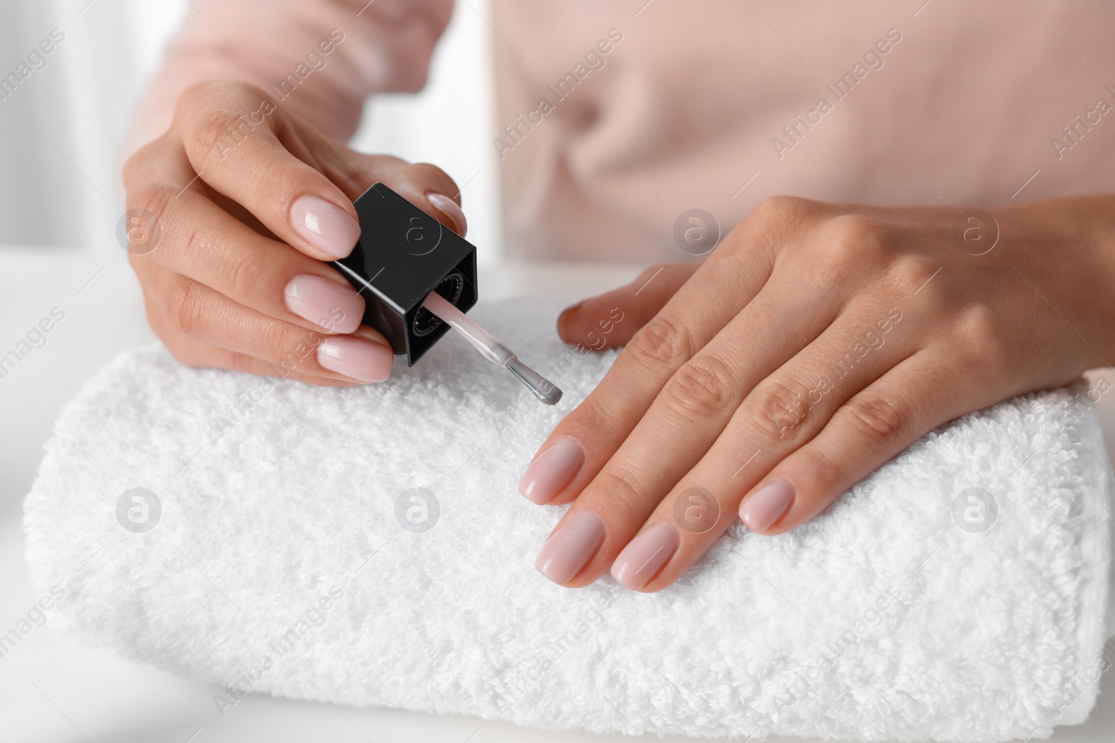 Photo of Woman applying nail polish at table, closeup. At-home manicure