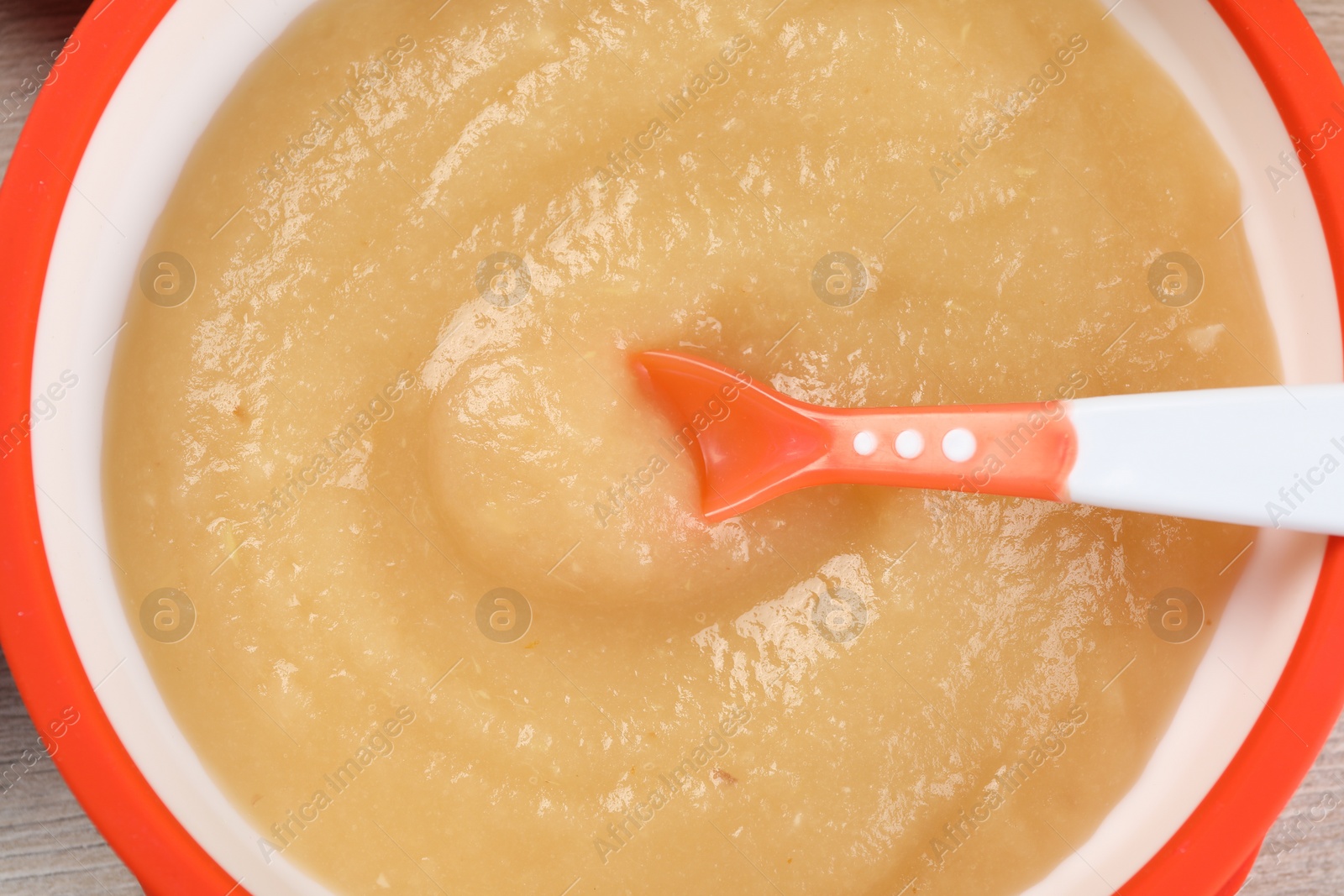 Photo of Healthy baby food. Bowl with delicious apple puree on white wooden table, closeup