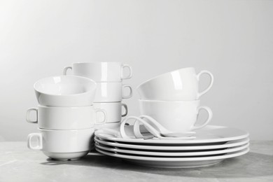 Photo of Set of clean dishware on grey table against light background