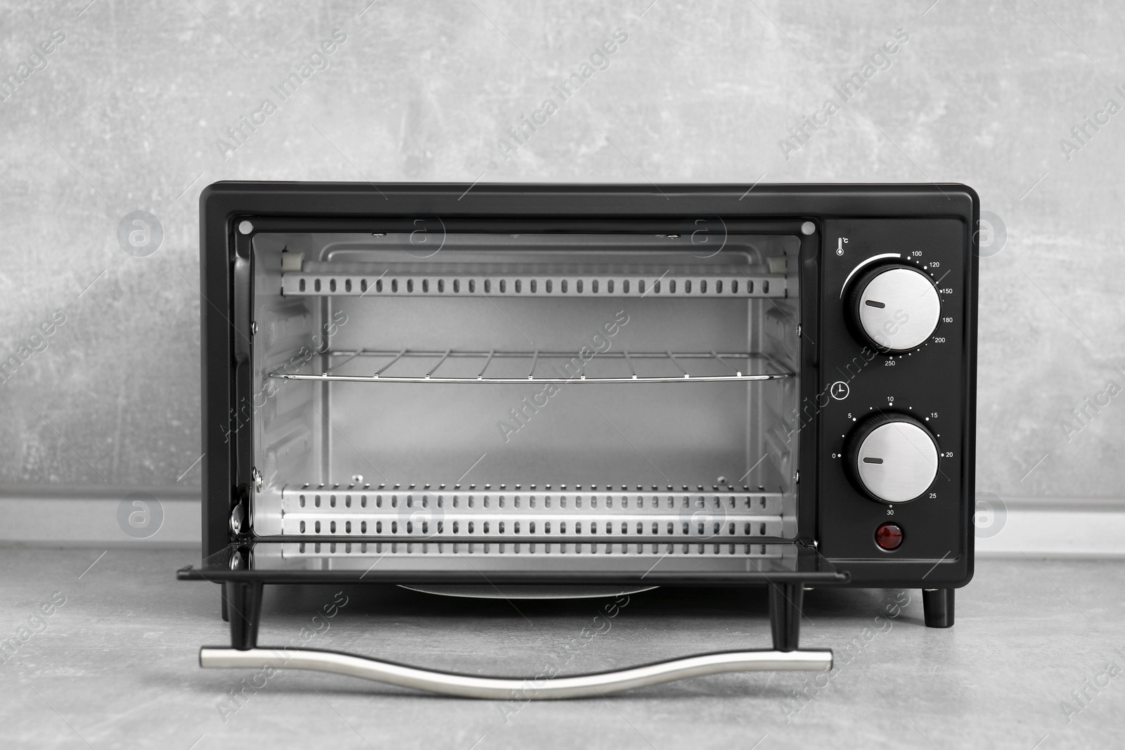 Photo of One electric oven on light grey table. Cooking appliance