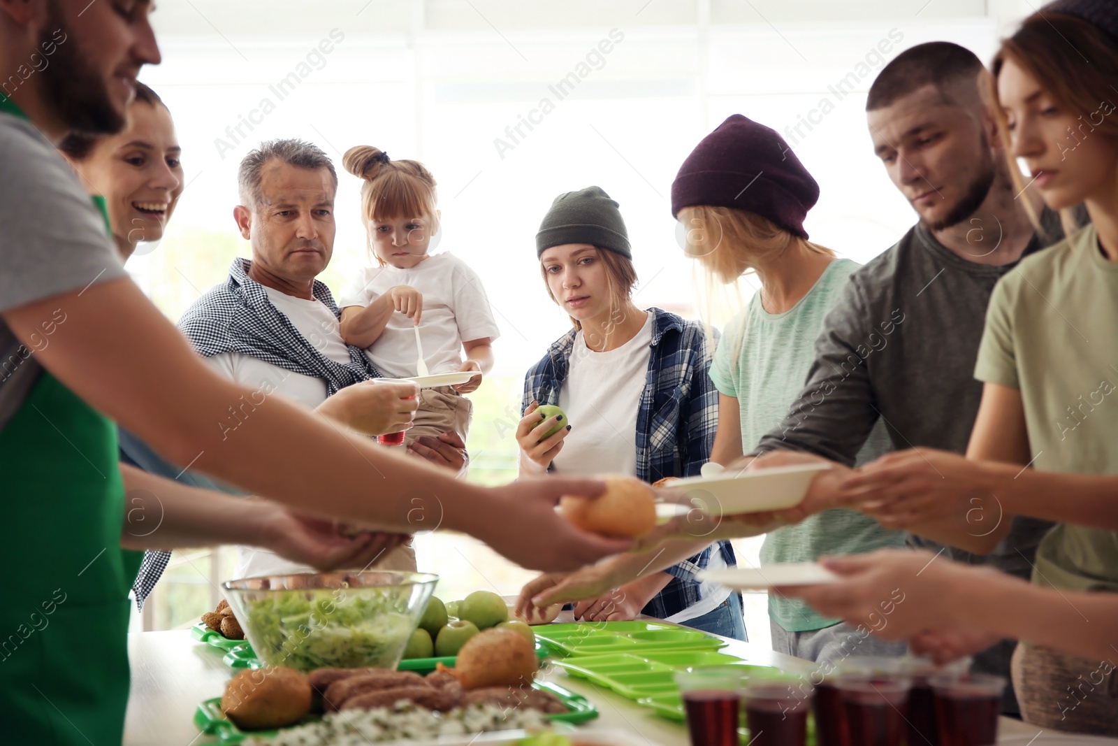 Photo of Volunteers serving food for poor people indoors