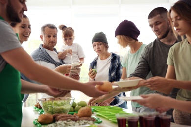 Volunteers serving food for poor people indoors