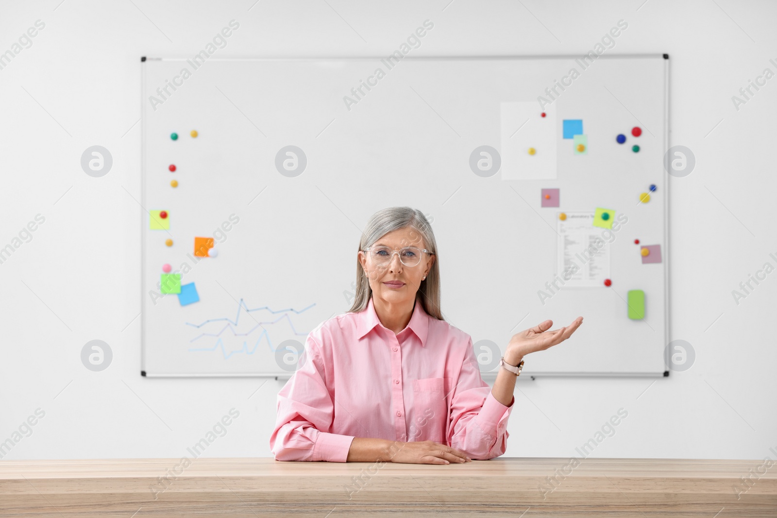 Photo of Professor giving lecture at desk in classroom