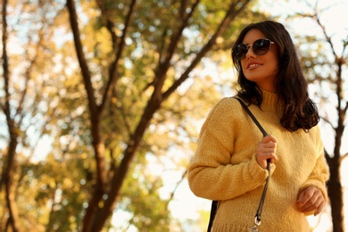 Photo of Beautiful young woman wearing stylish sweater in autumn park