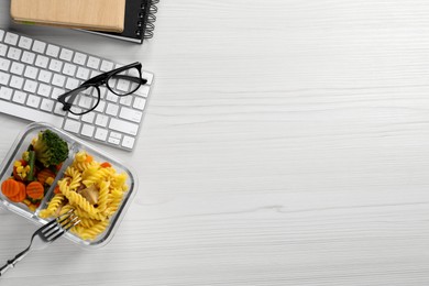 Photo of Container of tasty food, keyboard and glasses on white wooden table, flat lay with space for text. Business lunch