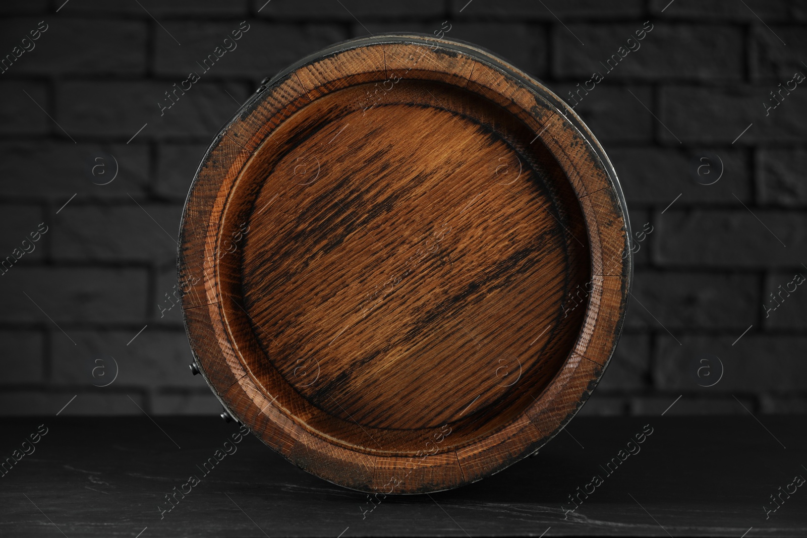 Photo of One wooden barrel on table near brick wall, closeup