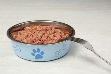 Photo of Bowl of wet pet food with fork on white table