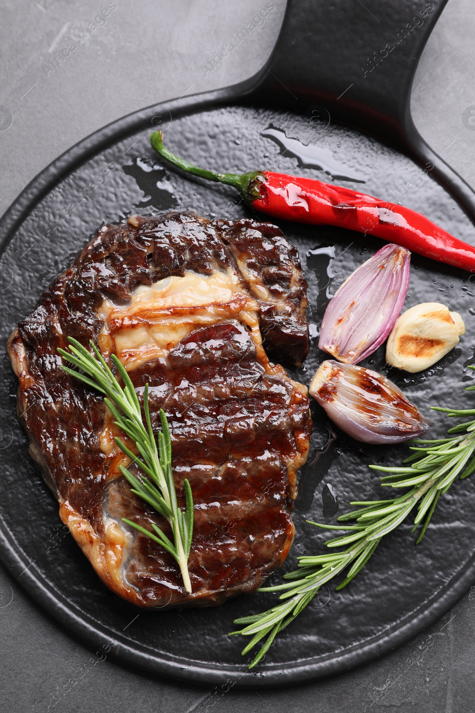 Photo of Delicious grilled beef meat, rosemary and spices on gray table, top view