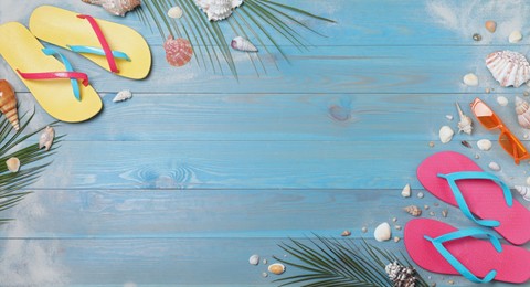 Photo of Stylish flip flops and beach objects on light blue wooden background, flat lay. Space for text