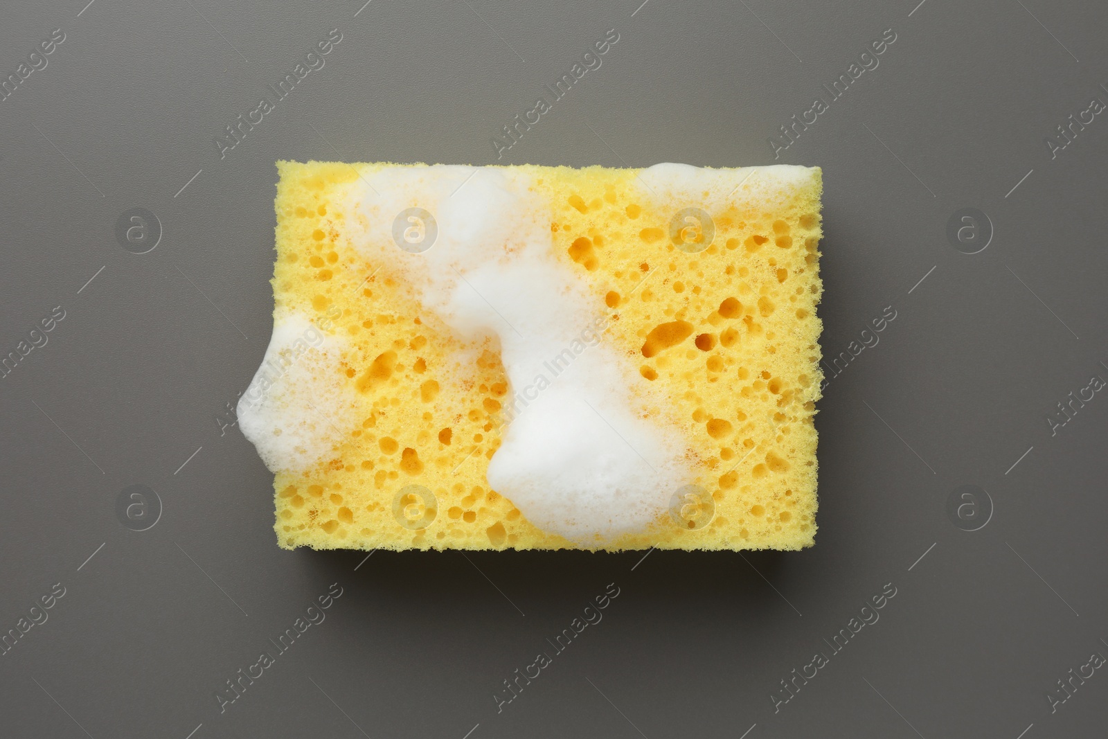 Photo of Yellow sponge with foam on grey background, top view