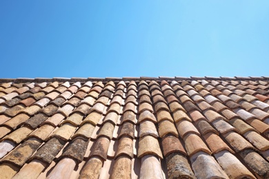 Photo of View of old roof tiles and blue sky on sunny day