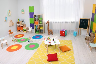 Child`s playroom with different toys and furniture. Cozy kindergarten interior