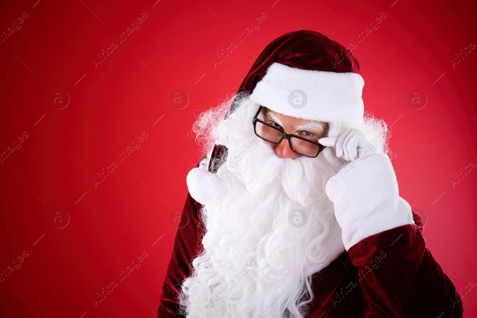 Photo of Portrait of Santa Claus with glasses on red background. Space for text