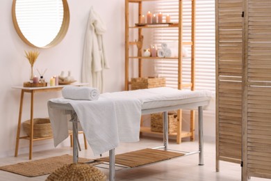 Photo of Comfortable massage table with clean towels in spa center